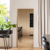 The Solene X full-length mirror (170×70 cm) with a wooden PS frame and 4mm double silver glass, displayed leaning vertically beside light curtains and a modern dining setup. The mirror beautifully reflects a warm wooden interior, indoor plants, and natural daylight from the window, highlighting its clear reflection and sleek minimalist design.