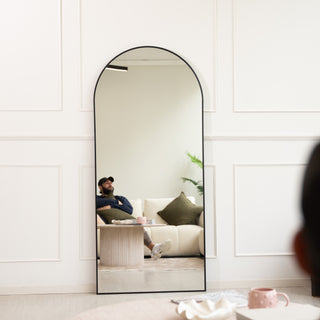 Modern arched Titan X full-length mirror with a sleek black aluminium frame and 4mm ultra-clear glass. Shown leaning elegantly against a wall in a contemporary living space, this mirror features a newly engineered back frame system for effortless wall mounting and a refined minimalist look perfect for New Zealand homes.