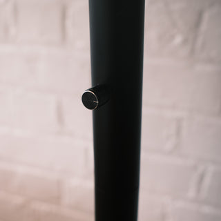 Extreme close-up of the rotary dimmer knob located on the matte black pole of the Trilogy 3-Light Floor Lamp. Features a knurled texture with a silver accent ring, allowing for easy brightness adjustment.