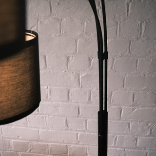 Close-up detail of the Trilogy 3-Light Floor Lamp's matte black metal stem. Shows the durable construction and neat cable management clips. The smooth finish and sturdy joinery highlight the quality craftsmanship.