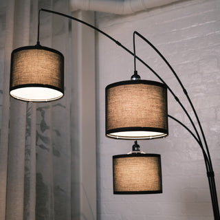 Low angle view looking up at the Trilogy 3-Light Floor Lamp. Reveals the interior of the three textured fabric drums and standard bulb sockets. The sweeping metal arms create a dynamic canopy effect.