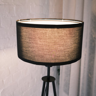 Close up of the Vanta floor lamp’s textured black fabric shade, softly illuminated to show its woven detail, with a warm neutral interior setting in the background.