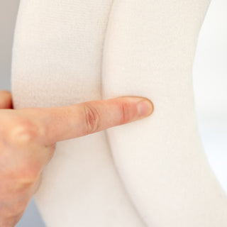 A close-up showcasing the plush cushioning of the Velora Wavy Mirror’s velvet frame. A finger presses into the soft, padded surface, highlighting its luxurious feel and high-quality craftsmanship. Perfect for adding a modern and elegant touch to any space.