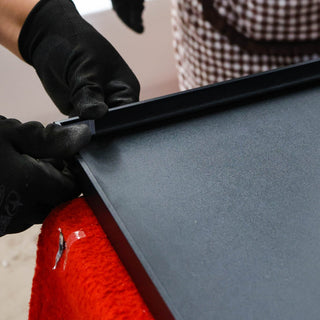 Close-up of a worker wearing gloves while securing the edge of a full-length mirror frame in the C&F Creations factory, ensuring precise assembly and durability.