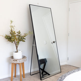 Zenith X full-length mirror 180x80cm displayed freestanding with back support, placed in a bedroom next to a plant, reflecting a bright and minimal interior.