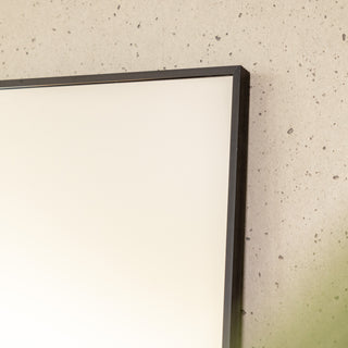 Close-up of the Zenith straight-edged full-length mirror showing its sleek 30 mm black aluminium frame and ultra-clear 3 mm glass. The detailed edge craftsmanship highlights the mirror’s premium build quality and minimalist aesthetic against a textured wall background.