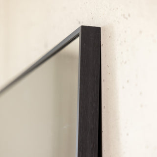 Detailed close-up of the Zenith straight-edged full-length mirror showing the precise 30 mm aluminium frame corner. The brushed black finish and ultra-clear 3 mm glass emphasise the mirror’s refined construction and elegant minimalist design, blending seamlessly against the textured wall surface.