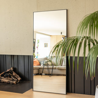 Zenith straight-edged full-length mirror sized 180 x 80 cm placed beside a modern fireplace, reflecting a cosy living room with neutral tones and natural light. The slim 30 mm aluminium frame and 3 mm ultra-clear glass showcase elegant craftsmanship, adding brightness and a sense of spaciousness to the home décor.