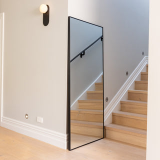 Zenith straight-edged full-length mirror sized 180 x 80 cm placed beside a staircase, reflecting clean architectural lines and natural light. The sleek 30 mm aluminium frame and ultra-clear 3 mm glass highlight its minimalist design, creating a bright and spacious atmosphere in a modern home interior.