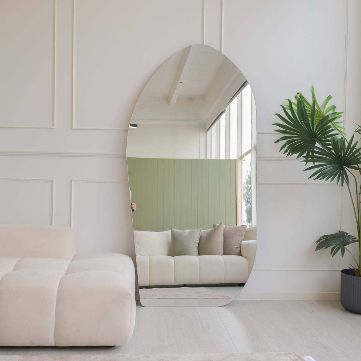 Cascade X irregular frameless full-length mirror reflecting a cream couch and sage green wall panel in an NZ lounge, C&F Creation