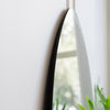 Close-up of the slim black edge of the Cascade X irregular frameless full-length mirror against a soft focus window, C&F Creation