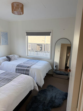 Bedroom with two beds, a mirror, and a window.